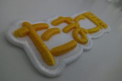 白い布地に黄色の糸で加工された3D刺繡ワッペンのアップ。