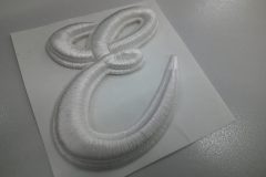 「E」文字の筆記体ロゴデザインを白糸で加工した、オリジナル3D刺繍ワッペンの制作事例。
