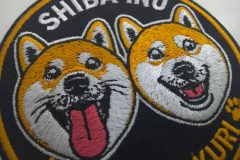 柴犬のキャラクター（二匹）が刺繍された、直径80mmのオリジナル刺繍ワッペン。キャラクター刺繍部分のアップ。