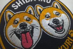 柴犬のキャラクター（二匹）が刺繍された、直径80mmのオリジナル刺繍ワッペン。キャラクター刺繍部分のアップ。