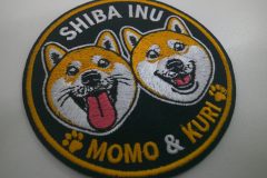 黒のエンブクロス生地に柴犬のキャラクター（二匹）が刺繍された、直径80mmのオリジナル刺繍ワッペン。