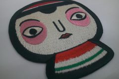 大きな顔が特徴的なこけしのキャラクター刺繍ワッペンの制作実例。