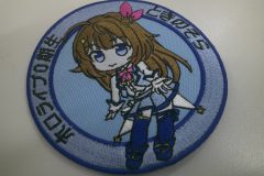 水色の生地の中心部に全身のデザインのキャラクターを刺繡した、オリジナル刺繡ワッペンの制作事例。