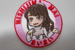 ピンクの衣装を着た女の子を中心にあしらい、周りをピンクと赤の糸で刺繡した、オリジナル刺繡ワッペンの制作実績。