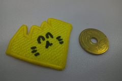 黄色い生地で形を模って、黒色で笑った顔を刺繡した、オリジナル刺繡ワッペンの制作実績。