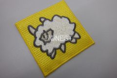 四角い黄色の生地の中心にもこもこの羊を刺繡した、オリジナル刺繡ワッペンの制作実績。