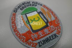 ビールジョッキに緑色の眼鏡と帽子を装着させた、発売者を彷彿させるような刺繡を施した、オリジナル刺繡ワッペンの制作実績。