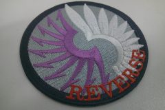グレーの生地に白と紫の糸でモチーフを刺繡した、オリジナル刺繡ワッペンの制作実績。