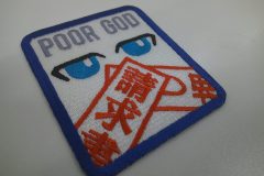 口元を赤色の糸で請求書や差し押さえの文字を刺繡し隠した顔の刺繡のオリジナル刺繡ワッペンの制作実績。
