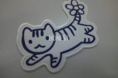 白色の生地に青色一色でしっぽにお花が咲いている猫の刺繡をしたオリジナル刺繡ワッペンの制作実績。