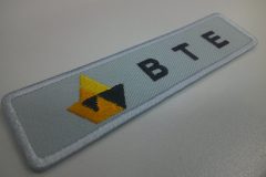 薄グレーの生地に企業名とロゴを刺繡した、オリジナル刺繡ワッペンの制作実績。