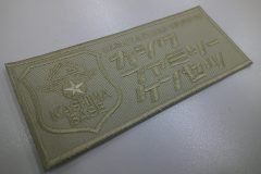 ベージュ系の生地にほぼ同色の糸で企業エンブレムとカタカナで見やすく工務店名を刺繡した、オリジナル刺繡ワッペンの制作実績。