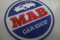 車屋の名前を中央に赤い糸で刺繍し、上部に車のイラストを刺繡した、オリジナル刺繡ワッペンの制作実績。