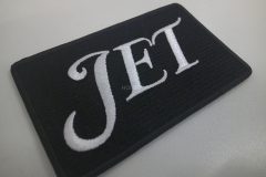 黒のクロス生地に白色の糸で大きく文字を刺繡したオリジナル刺繡ワッペンの制作実績。