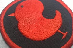 黒い生地に赤い糸で横向きの小鳥を大きく刺繡した、オリジナル刺繡ワッペンの制作実績のアップ。