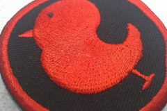 黒い生地に赤い糸で横向きの小鳥を大きく刺繡した、オリジナル刺繡ワッペンの制作実績のアップ。