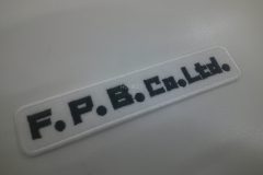 白のフェルト生地に黒色の糸で会社名を刺繡した、オリジナル刺繡ワッペンの制作実績。