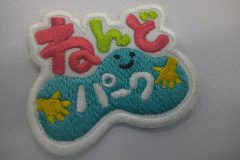 ピンクと黄緑のポップな色合いの文字と粘土をこねている様子を刺繡した、オリジナル刺繡ワッペンの制作実績。