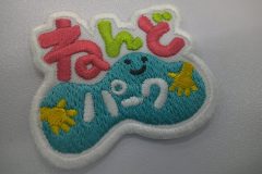 ピンクと黄緑のポップな色合いの文字と粘土をこねている様子を刺繡した、オリジナル刺繡ワッペンの制作実績。