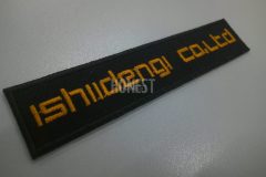 黒い生地にオレンジ色の糸で電気会社の社名を刺繡した、オリジナル刺繡ワッペンの制作事例。