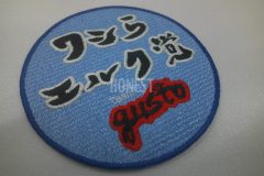 薄サックス色の生地に白縁の黒字と赤縁の黒字でチーム名を刺繡した、オリジナル刺繡ワッペンの制作事例。