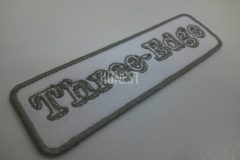 白色の生地に、グレーの糸で変わったアルファベットの文字デザインで名前を刺繡した、オリジナル刺繡ワッペンの制作事例。