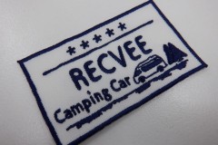 白色の生地にネイビーの糸でワンボックスタイプの車と木々が会社名と共に刺繡されたオリジナル刺繡ワッペンの制作実績。