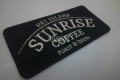 黒い生地にメタリックシルバーの糸で島の名前と店舗名を刺繡した、オリジナル刺繡ワッペンの制作事例。