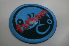 黒色の生地に明るい青色の糸でメーカーロゴを大きく刺繡し、その上にメーカー名を重ねて刺繡した、オリジナルワッペンの制作事例。