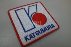 白のエンブクロスを土台とし、建設会社のロゴを刺繍した制作事例。形状は正方形の角丸型。