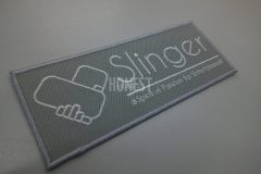 握手をしているようなロゴが印象的な企業のオリジナル刺繍ワッペン。シルバーグレー生地に白糸単色でスタイリッシュな仕上がり印象。