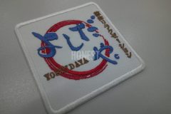白のアーバンツイル生地にマッサージ店の和風なロゴを忠実に再現し加工した、店舗用の刺繍ワッペン。