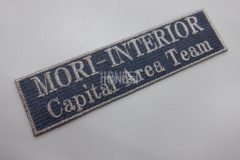 濃いグレーのクロス生地に銀糸で社名を刺繡したオリジナル刺繡ワッペンの制作実績。
