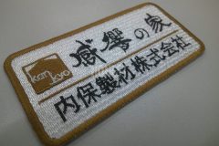 白のエンブクロス生地に製材会社のロゴを刺繍加工したワッペン。会社名は筆文字で雰囲気出しに優れた仕上がり。