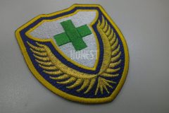 警備会社のロゴを濃い黄色・白・緑の糸で加工した、オリジナル刺繍ワッペン。盾形のエンブレム調の仕上がり。
