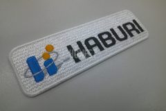 白のエンブクロス生地に土木工事会社の社名ロゴを刺繍した、オリジナルワッペンの制作事例。