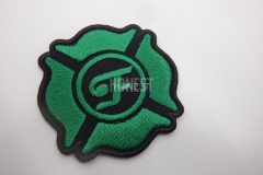 緑色の刺繍糸で四葉の校章のようなデザインの中心に文字が刺繡されたオリジナル刺繡ワッペンの制作実績。