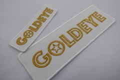 白い生地に金糸で会社名を刺繡した大きさの異なる二種類のオリジナル刺繡ワッペンの制作実績。