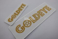 白い生地に金糸で会社名を刺繡した大きさの異なる二種類のオリジナル刺繡ワッペンの制作実績。