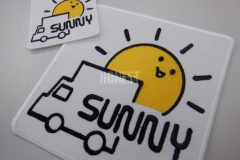 白の生地にトラックと顔のついた大きな太陽、会社名を刺繡したオリジナル刺繡ワッペンの制作実績。