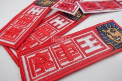 赤い生地に赤・白で会社名を、横にツタンカーメンも刺繡したオリジナル刺繡ワッペンの制作実績。