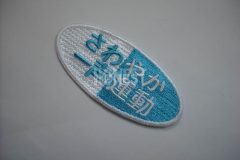 白と水色の糸で活動名を刺繡した、オリジナル刺繡ワッペンの制作実績。