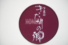 エンジ色のツイル生地に白糸で施設名を刺繡した、オリジナル刺繡ワッペンの制作事例。