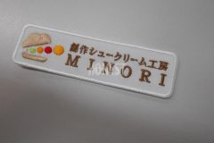 カラフルな円を挟んだシュークリームと店舗名を白い生地に刺繍した、オリジナル刺繡ワッペンの制作事例。