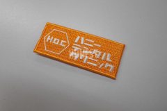 オレンジ色の生地に白糸で病院名を刺繡した、オリジナル刺繡ワッペンの制作事例。