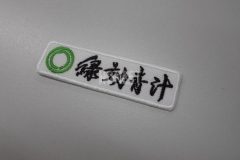 白色の生地に黄緑色で二重丸と黒色で商品名を刺繡した、オリジナル刺繡ワッペンの制作事例。
