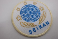 青色で模様が細かい円と金色で下から羽で包み込むようなデザインのオリジナル刺繡ワッペンの制作実績。