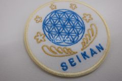 青色で模様が細かい円と金色で下から羽で包み込むようなデザインのオリジナル刺繡ワッペンの制作実績。
