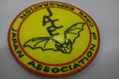 黄色のクロス生地に黒糸で企業名とコウモリの絵を刺繡し赤糸で囲んだ、オリジナル刺繡ワッペンの制作事例。