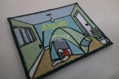 部屋の中にテントを立てて中で寝ているイラストを総刺繡した、オリジナル刺繡ワッペンの制作事例。